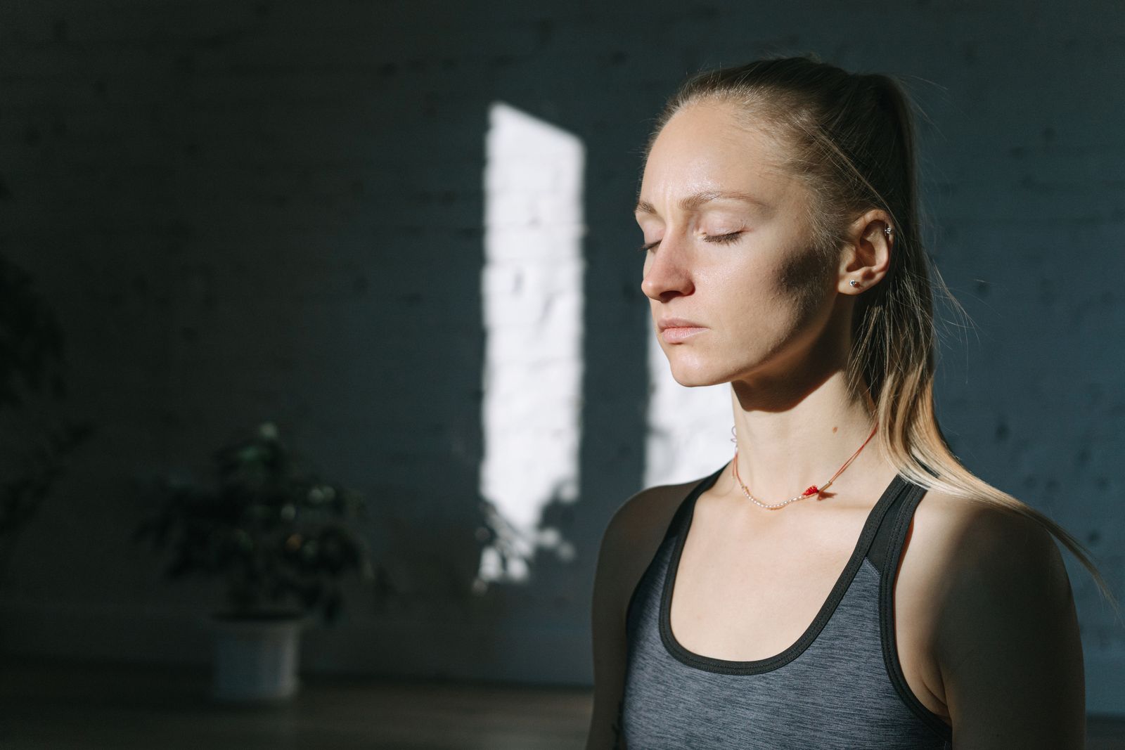 Woman calmly meditating with her eyes closed in a sunlit room