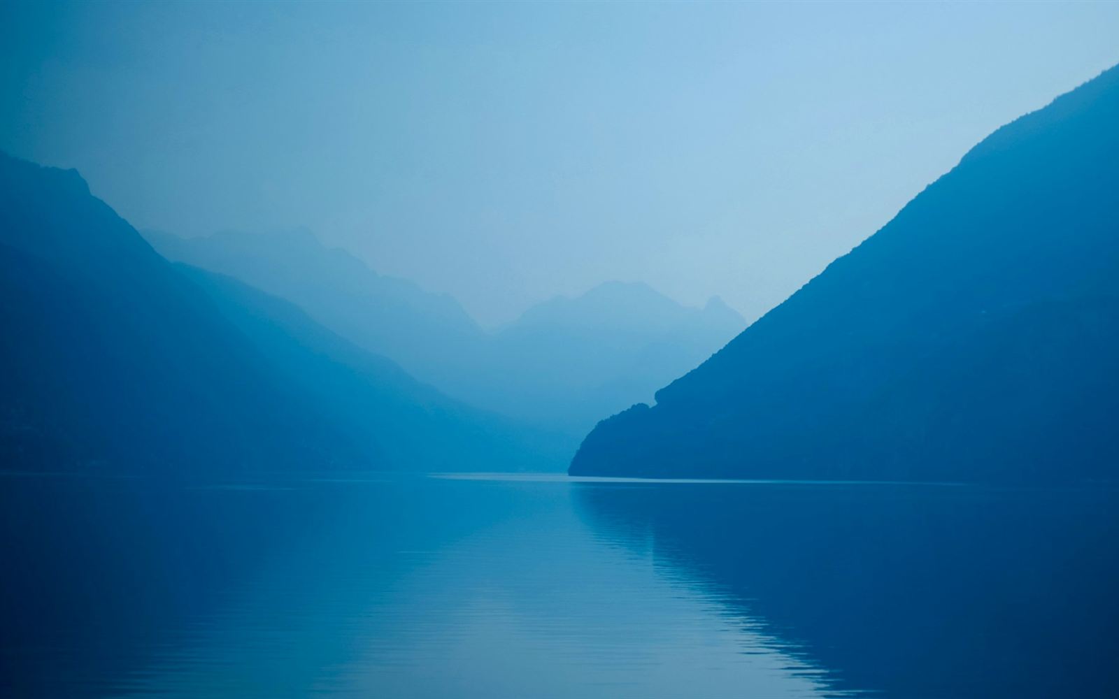 Still, misty blue lake between mountains, representing a calm fresh start